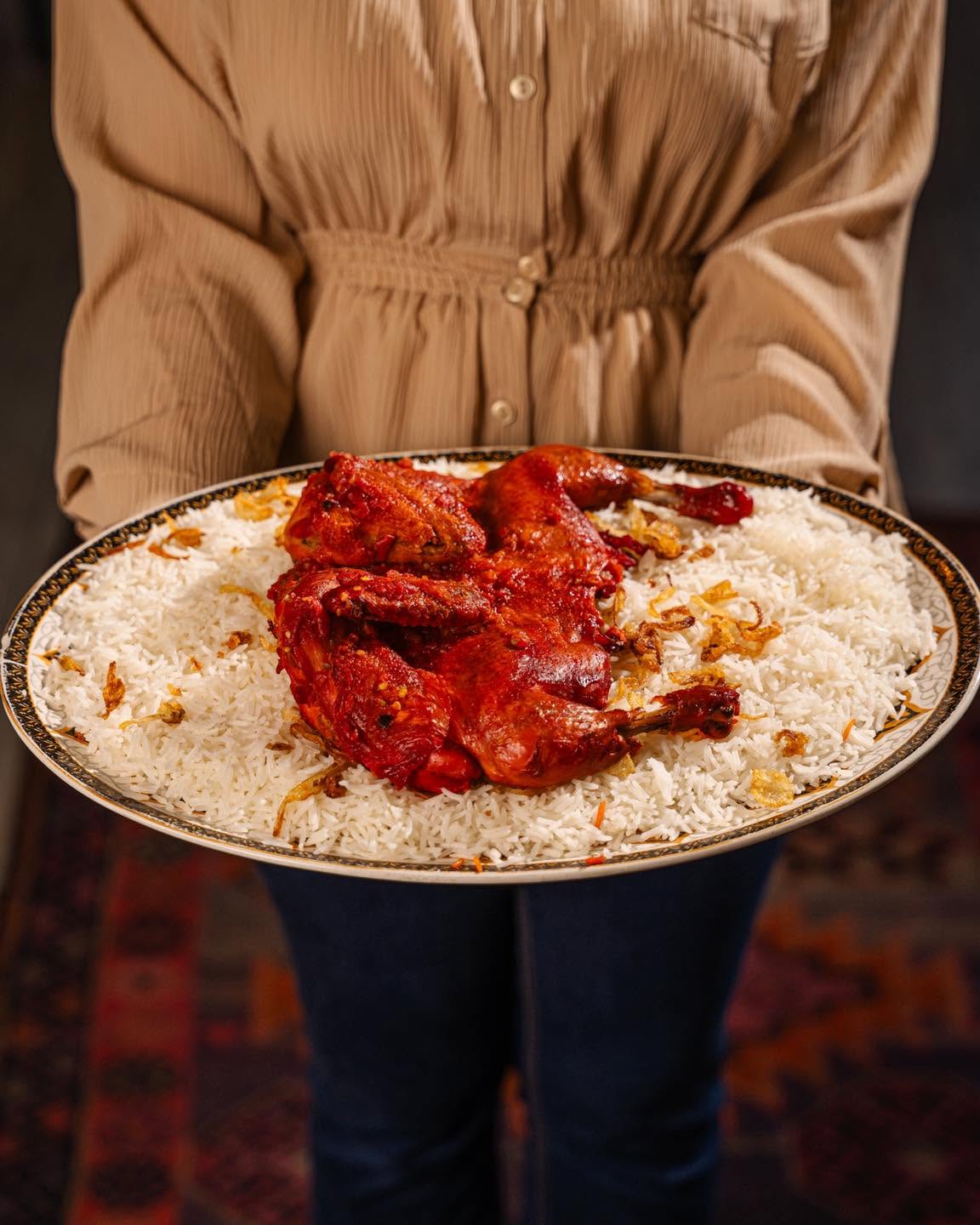 قاپێکی گەورەی مەندی مریشک لەسەر سەری پیاوێک بە جەمەدانی سوور لە کاتی خۆرئاوابوون